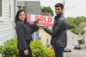 A realtor turning over a key to a new buyer after selling a house
