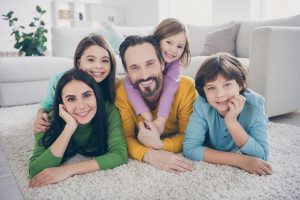a happy family sitting together on a nice clean carpet enjoying the fresh air in their home air duct & carpet cleaning services